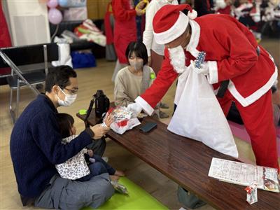 サンタさんからクリスマスプレゼントを受け取る親子