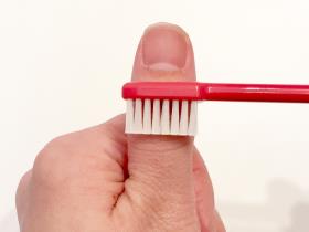 歯ブラシのヘッドを親指に当てて、幅を確認している写真